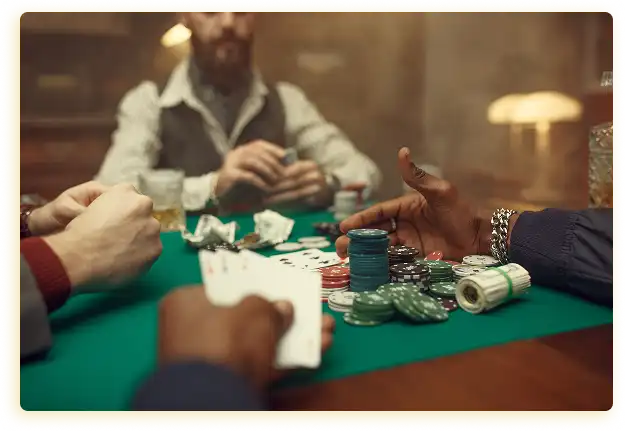 Op de afbeelding is een gezellige pokerruimte te zien, die de sfeer van een spannend en gezellig feestje uitstraalt. In het midden van het beeld staat een groene speeltafel waarop talrijke pokerfiches in verschillende kleuren en maten liggen, evenals kaartcombinaties en enkele lege servetten. Op de tafel ligt ook een klein rolletje met speelstenen of munten.