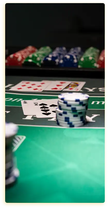 Op de foto is een scène aan een pokertafel te zien. Het kleurenschema bestaat voornamelijk uit donkere tinten, met accenten in de vorm van de groene tafel en de felle kleuren van de fiches en kaarten, wat het beeld een speelse sfeer geeft.